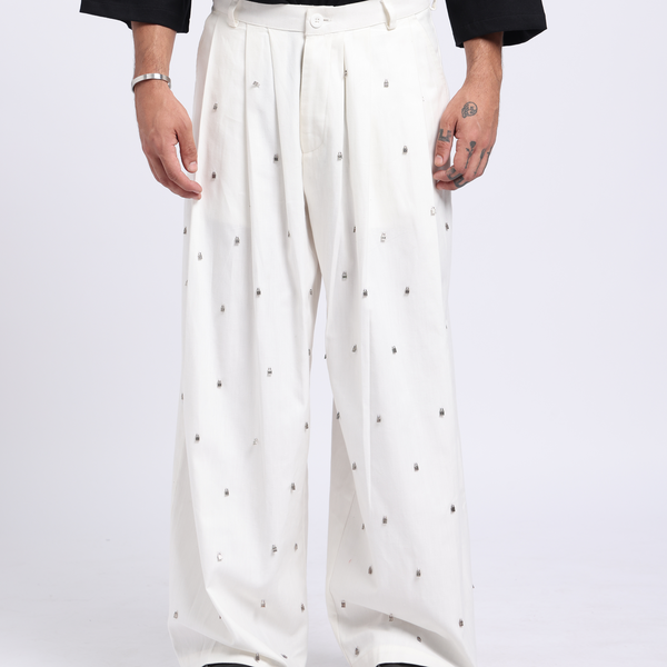 Person wearing a black oversized t-shirt with a white design and white pants with black dots on a white background
