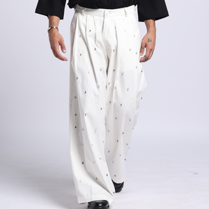 Man wearing a black t-shirt with a white logo and white pants on a white background
